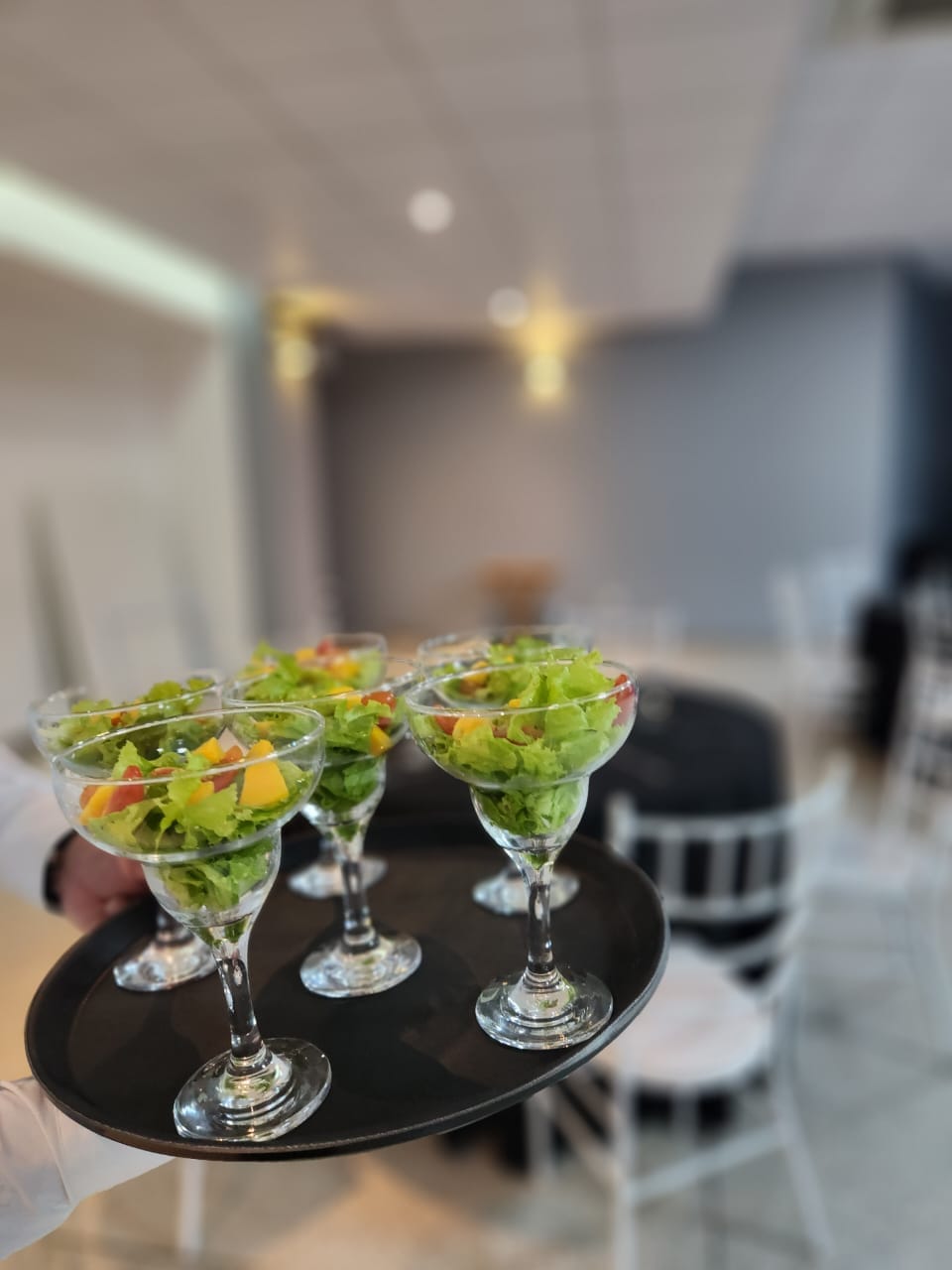 Garçom servindo saladas em taças durante o evento