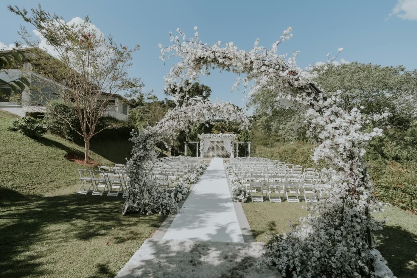 Altar montado ao ar livre com arcos de flores brancas